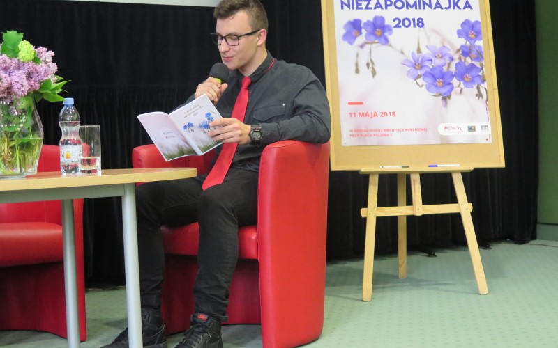 Wychowanek koszalińskiego Pałacu Młodzieży siedzi na czerwonym fotelu przy stoliku i...
