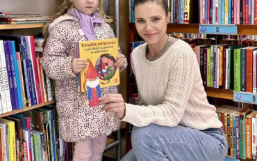 Dziewczynka z bibliotekarką prezentuje książeczkę
